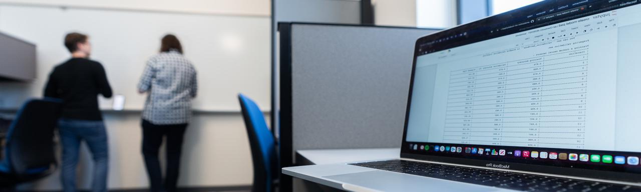 classroom with a laptop open and students in the background